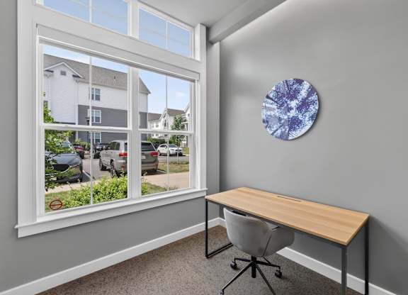 Reservable workspace with a desk, chair, window, and abstract wall art.