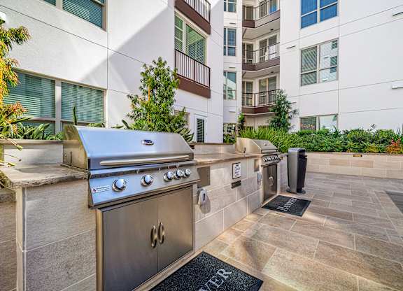 Outdoor barbecue stations with stainless steel grills, set within beautifully landscaped courtyards