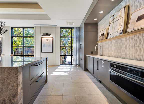 Chef-inspired catering kitchen with quartz countertops, modern cabinetry, and statement backsplash