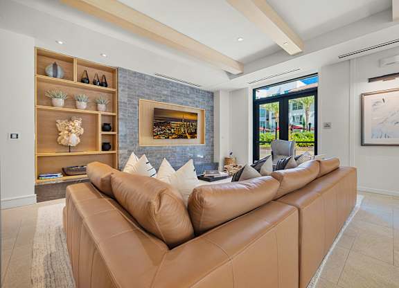 Elegant clubroom lounge featuring a leather sectional, custom shelving, and large-screen TV for movie nights