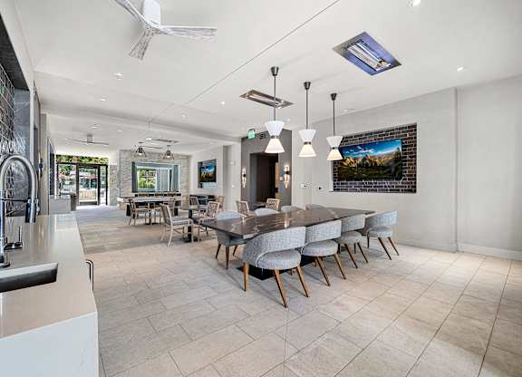 Clubroom with a long dining table, plush seating, and entertainment screens designed for community gatherings