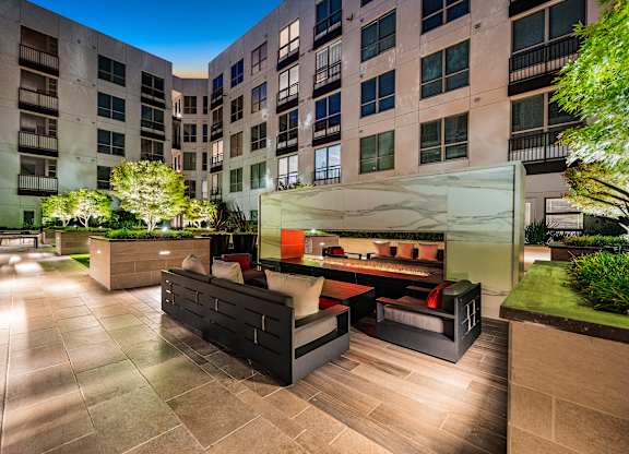 Elevated courtyard lounge with marble-accented fire feature, modern seating, and ambient night lighting