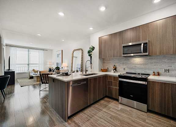 Sleek open kitchen with quartz counters and ample cabinetry that flows into a bright living area
