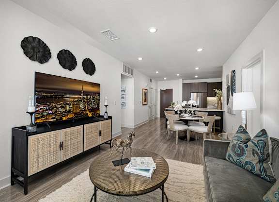 Stylish living space with soft textures, a sleek media console, and wide windows for abundant light