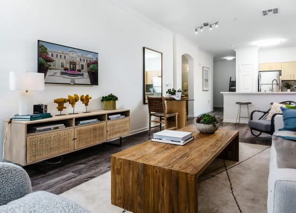 Pet-Friendly Apartments in Rancho Cucamonga, CA - Villas at the Gardens - Open Concept Living Room With Wall Mounted Television, Wood Coffee Table, And Breakfast Bar Kitchen.