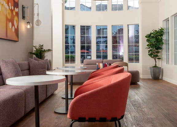 "Resident Lounge Featuring Cozy Seating, Dining Tables, and Tall Windows  "