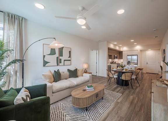 Furnished living and dining area with wood-style flooring, large windows, and an open kitchen.