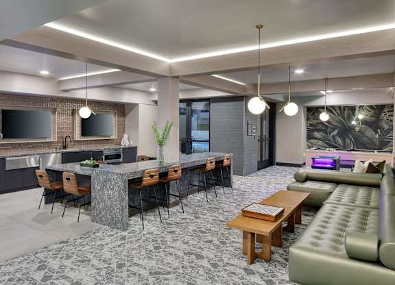 Game lounge with a communal table, counter seating, arcade games, sofas, and televisions.