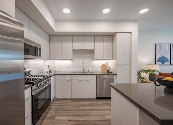 Kitchen with white cabinetry, quartz counters, stainless steel appliances, and recessed ceiling lights.