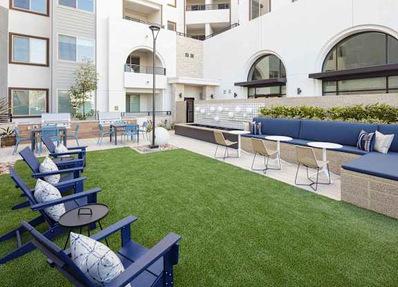Outdoor courtyard with turf, blue lounge chairs, built-in banquette seating, and a counter.