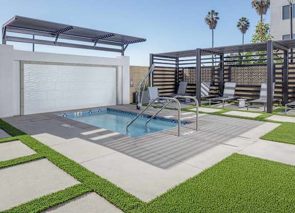 Outdoor spa with metal handrails, a shaded pergola, lounge seating, and geometric paving.