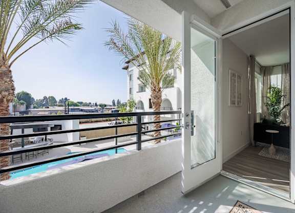 Private apartment balcony with a metal railing and views of the pool courtyard.