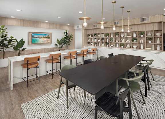 Resident lounge with a communal table, counter seating, open shelving, and a kitchenette.