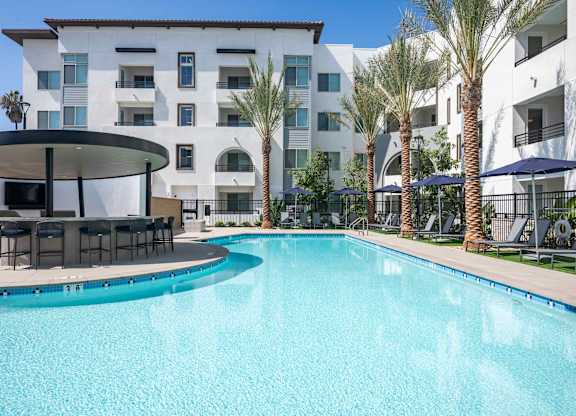 Resort-style pool with the Round Bar, palm trees, lounge seating, and apartment buildings.