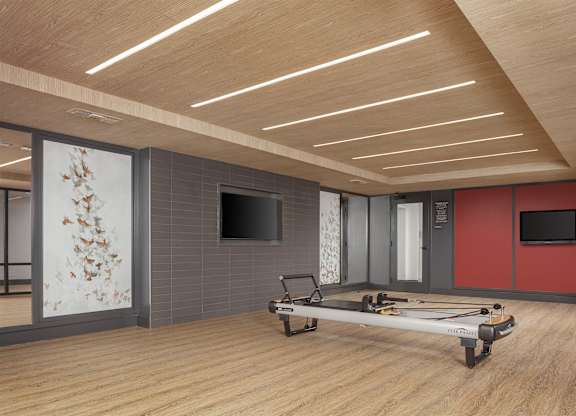 Fitness studio with wood flooring, wall mirrors, ballet barres, exercise mats, and televisions.