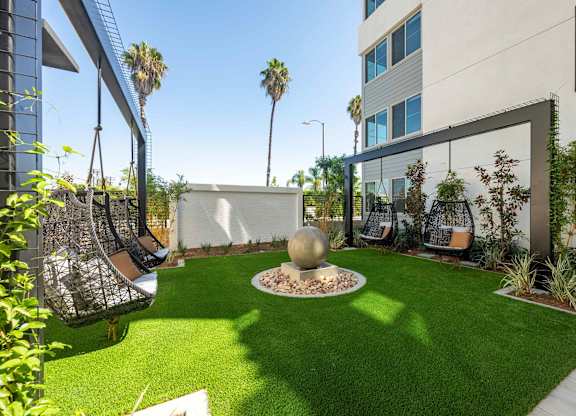 Zen Garden with hanging chairs, green turf, landscaped walls, and a round water feature.