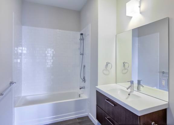 Bathroom with white tile tub and dark vanity at 750 Summer Street Apartments, Stamford, CT