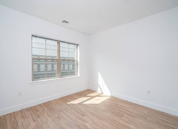 Empty bedroom with hardwood flooring and window at Port & Main Apartments, Port Chester, New York