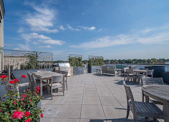 Rooftop terrace with dining tables and waterfront views at Port & Main Apartments, Port Chester, NY