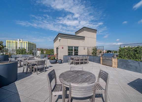 Rooftop terrace with dining tables and grill stations at Port & Main Apartments, Port Chester, New York