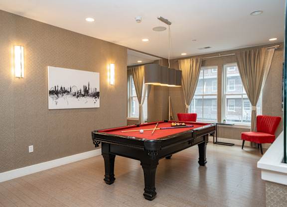 Billiards room with red felt table and seating at 750 Summer Street Apartments, Stamford