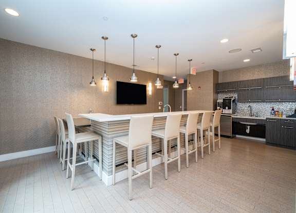 Community kitchen with bar seating and pendant lights at 750 Summer Street Apartments, Connecticut, 06901