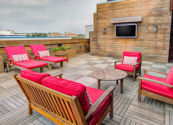 Rooftop lounge with red cushioned seating and tv at 750 Summer Street Apartments, Stamford, CT