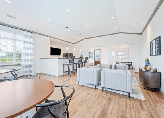 a resident clubhouse with couches tables and chairs and a kitchenette