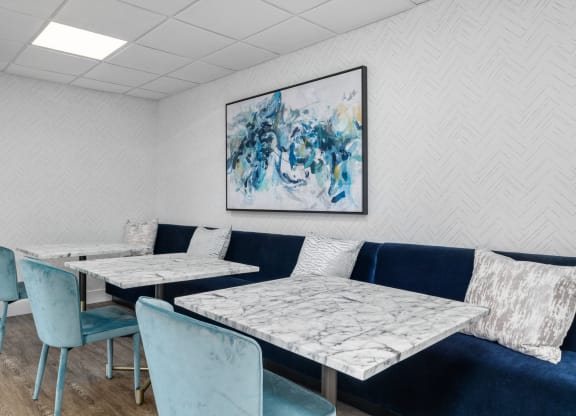 a seating area with blue chairs and white tables with marble tops