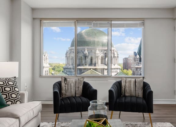 a living room with two black chairs and a large window with a view of the dome of