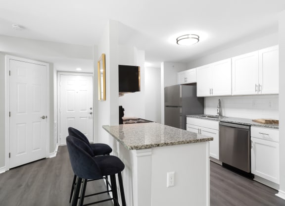 a kitchen with an island and a counter top with black chairs