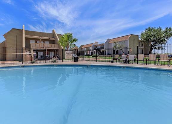 a swimming pool in front of a building with apartments in the background