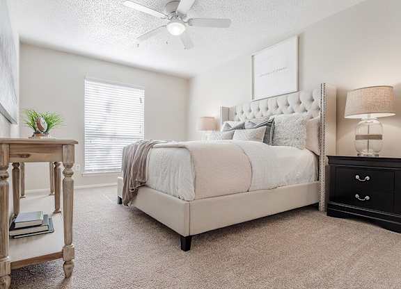 a white bedroom with a large bed and a night stand