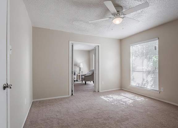 an empty living room with a ceiling fan