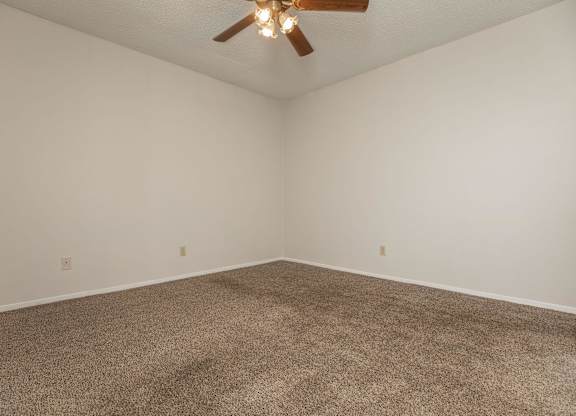 an empty room with carpet and a ceiling fan