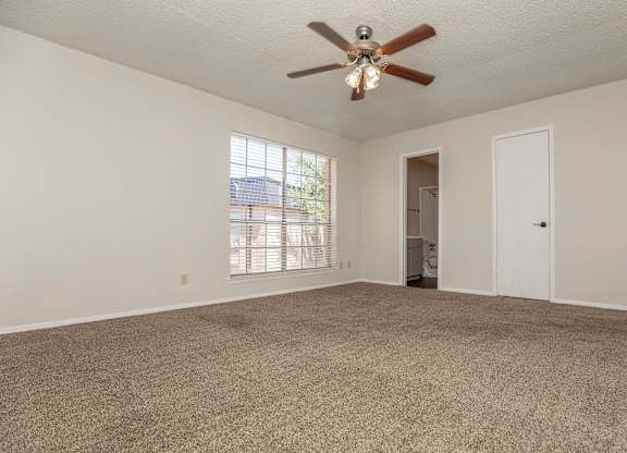 an empty living room with a ceiling fan and a window