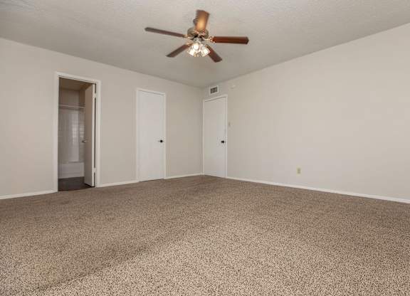 a spacious living room with carpet and a ceiling fan