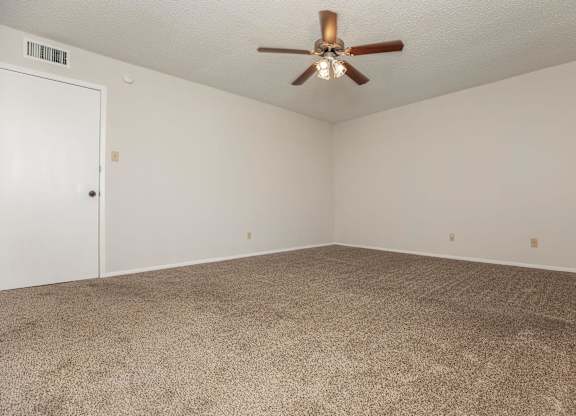an empty living room with carpet and a ceiling fan