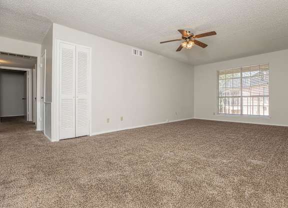 an empty living room with a ceiling fan and a window