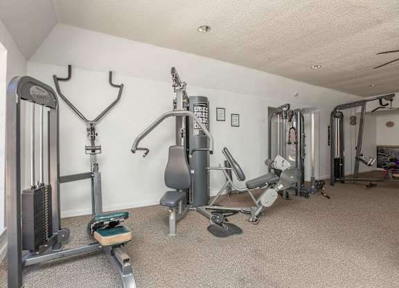 A home gym with a variety of equipment including a treadmill, weights, and a bench press.