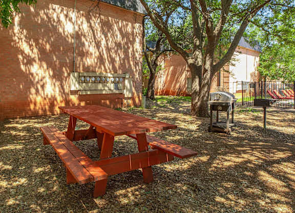 a picnic table in the yard of a building with a grill