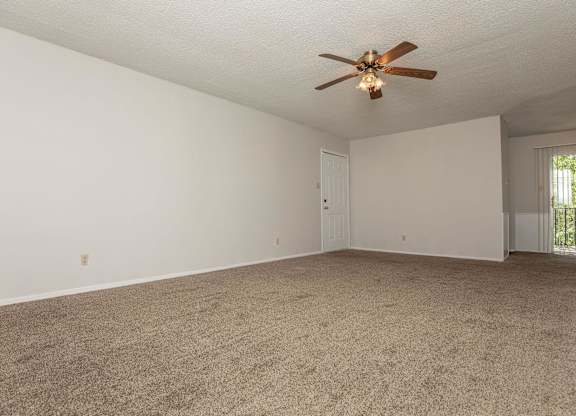 an empty living room with a ceiling fan