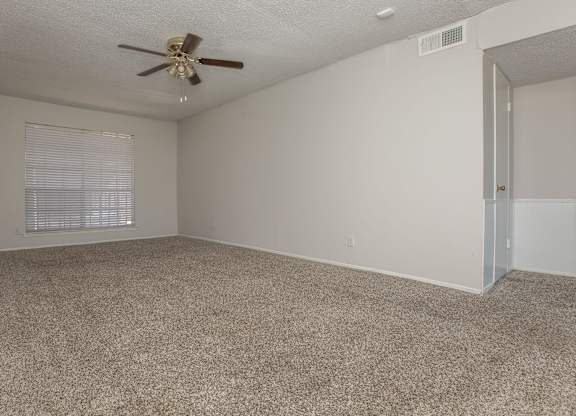 an empty living room with carpet and a ceiling fan