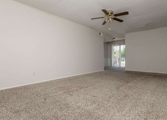 an empty living room with carpet and a ceiling fan