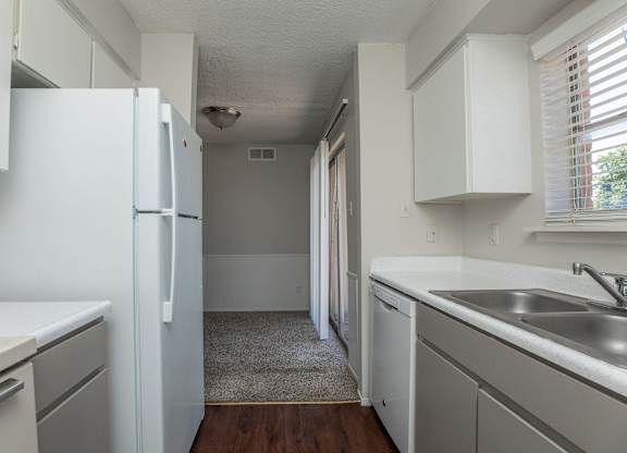 an empty kitchen with white cabinets and a white refrigerator
