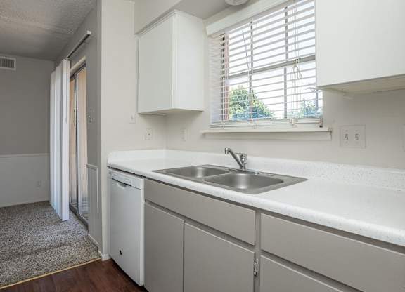 a kitchen with white cabinets and a sink and a window
