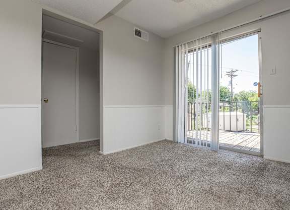 an empty living room with a sliding glass door to a balcony
