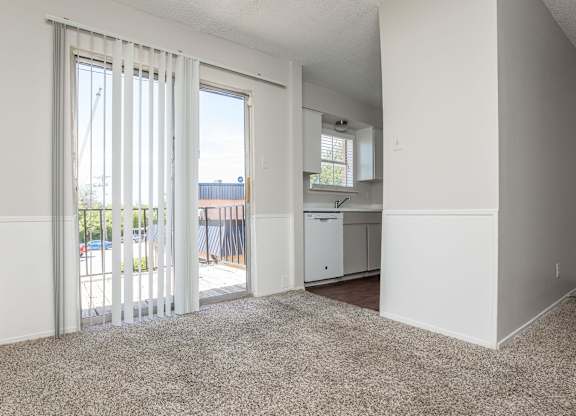 an empty living room with sliding glass doors to a kitchen