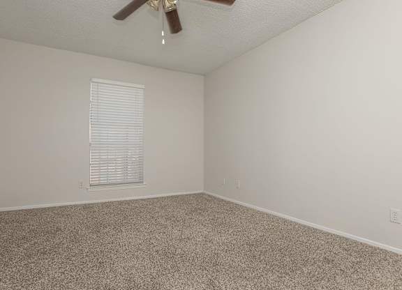 an empty room with carpet and a ceiling fan