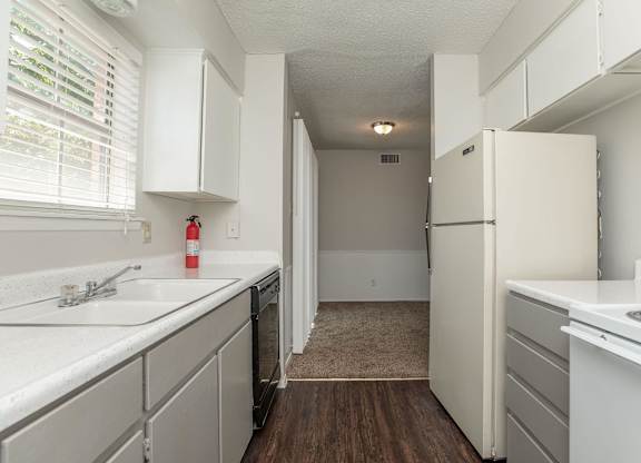 an empty kitchen with white cabinets and a white refrigerator and sink